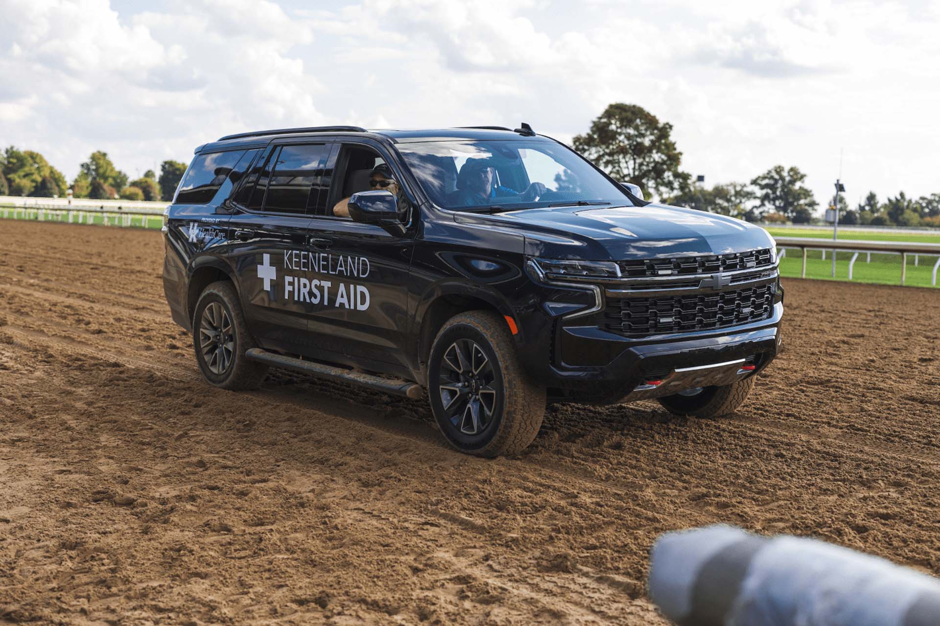 A picture of the Fasthorsepro First Aid car on the dirt track. It is a large black Chevy SUV.