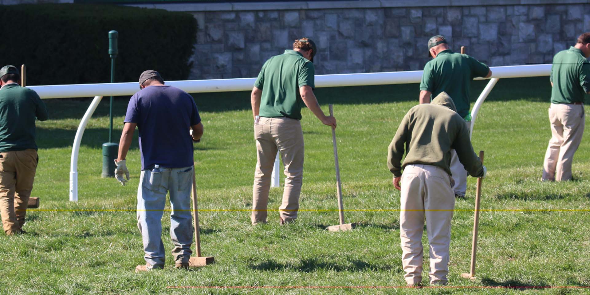 An action shot of Fasthorsepro team members tamping down turf divots.